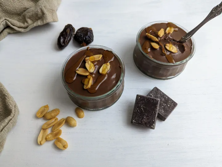 Chocolate topped oatmeal in glass cups topped with honey and peanuts