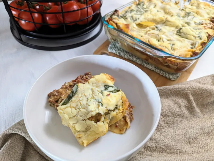 Lasagna in a white bowl next to a casserole fish with more lasagna