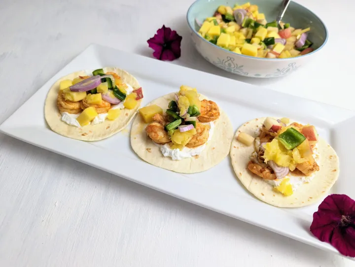 Close up image of a shrimp taco with peach mango salsa on a white plate