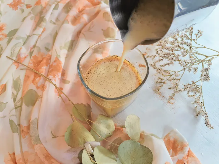 Frothed milk being poured into cold brew coffee